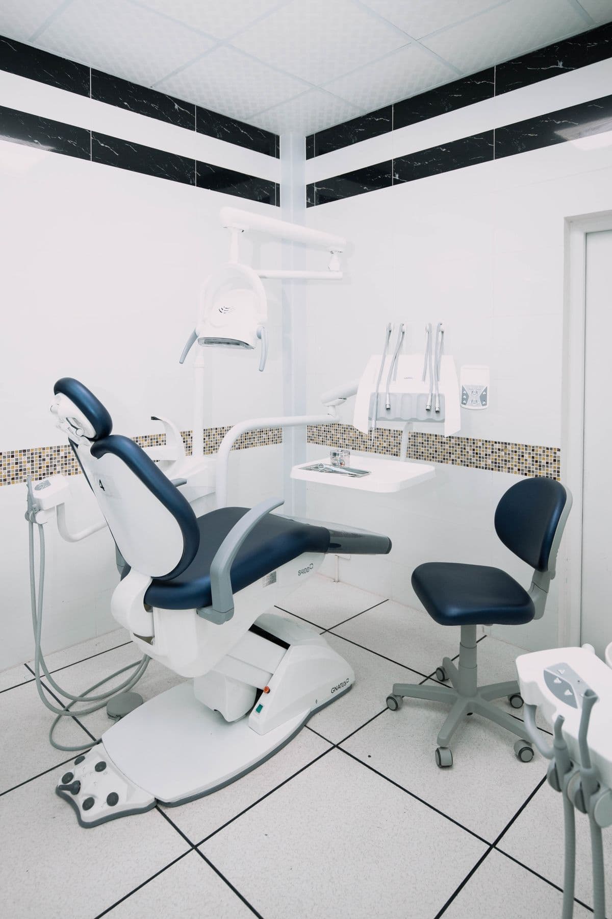 A clean, modern dental treatment room with a navy dental chair and equipment